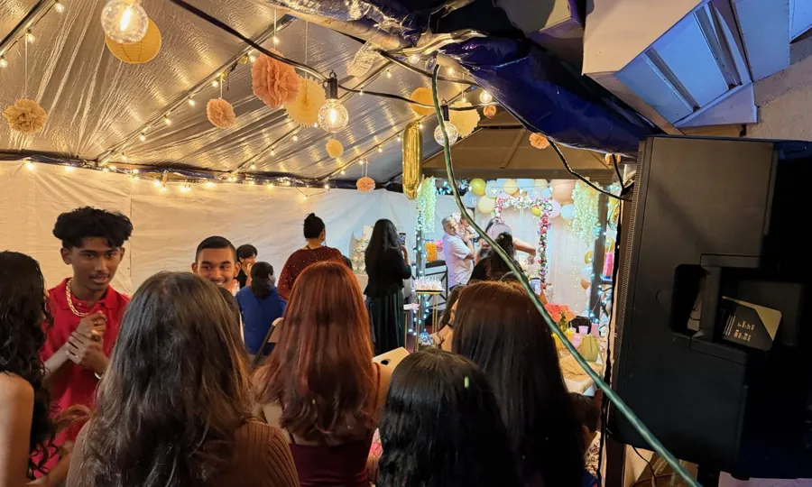 Teens celebrating at a birthday party in a string-lit tent
